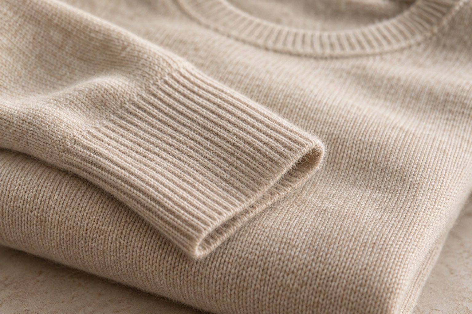 Close-up of the rib cuff on a folded oatmeal cashmere sweater